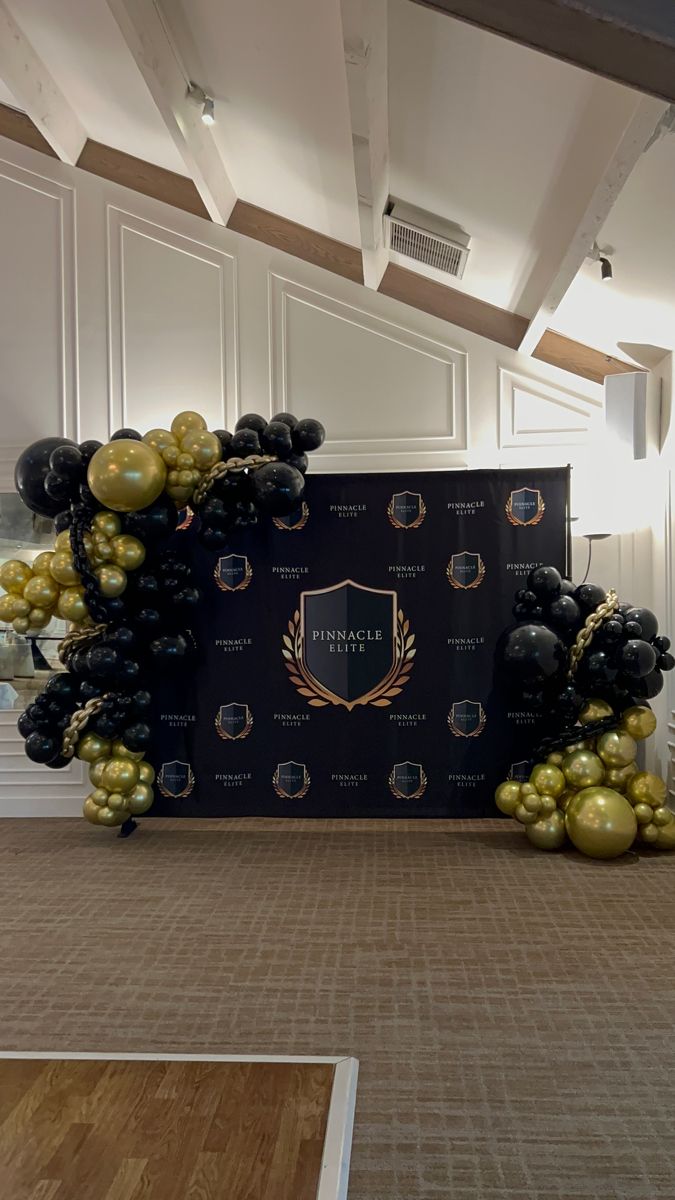 a black and gold balloon arch in the middle of a room