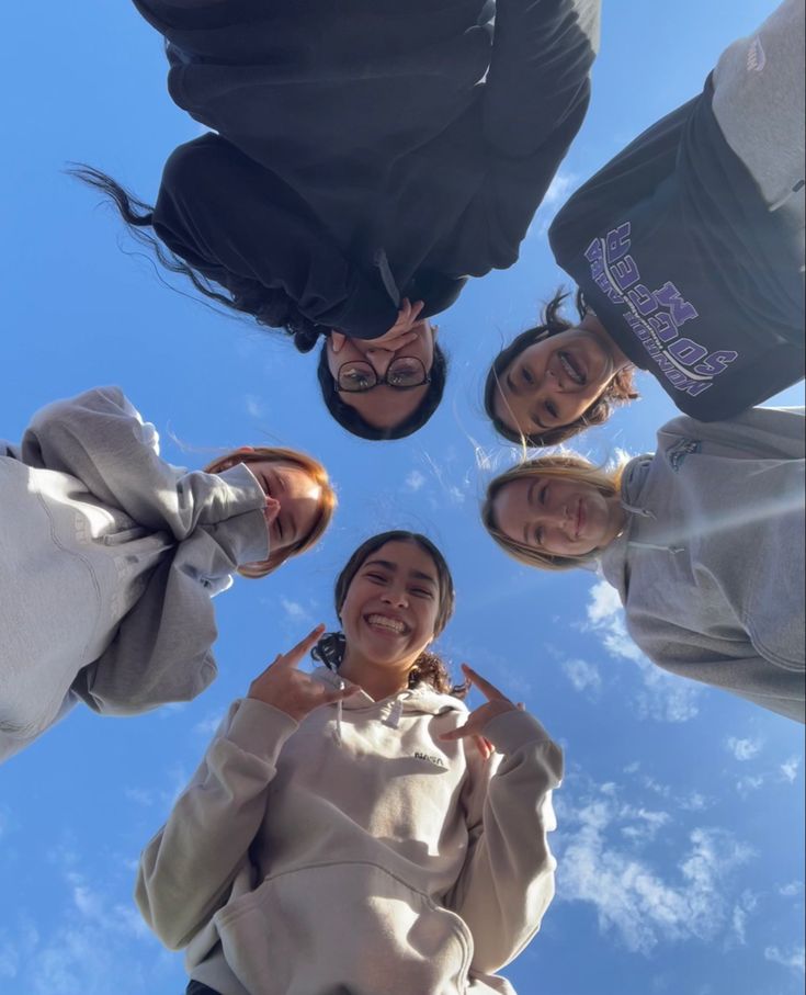 four people standing in a circle looking up at the sky