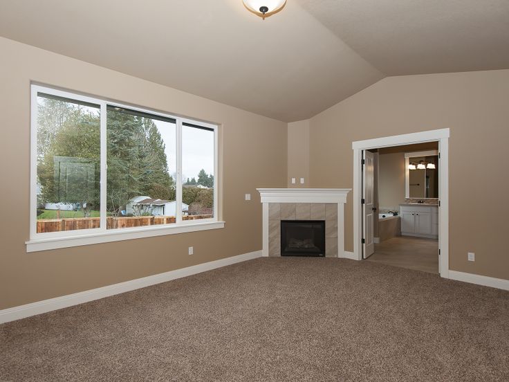 an empty living room with a fireplace and large windows in the middle of the room