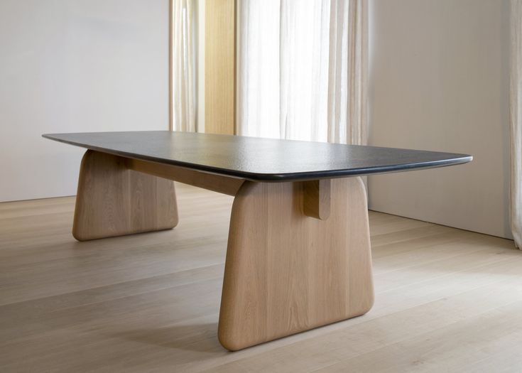 a wooden table sitting on top of a hard wood floor next to a white wall