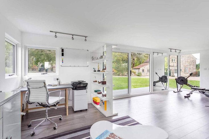 a home gym with exercise equipment in the living room and large windows looking out onto an open yard