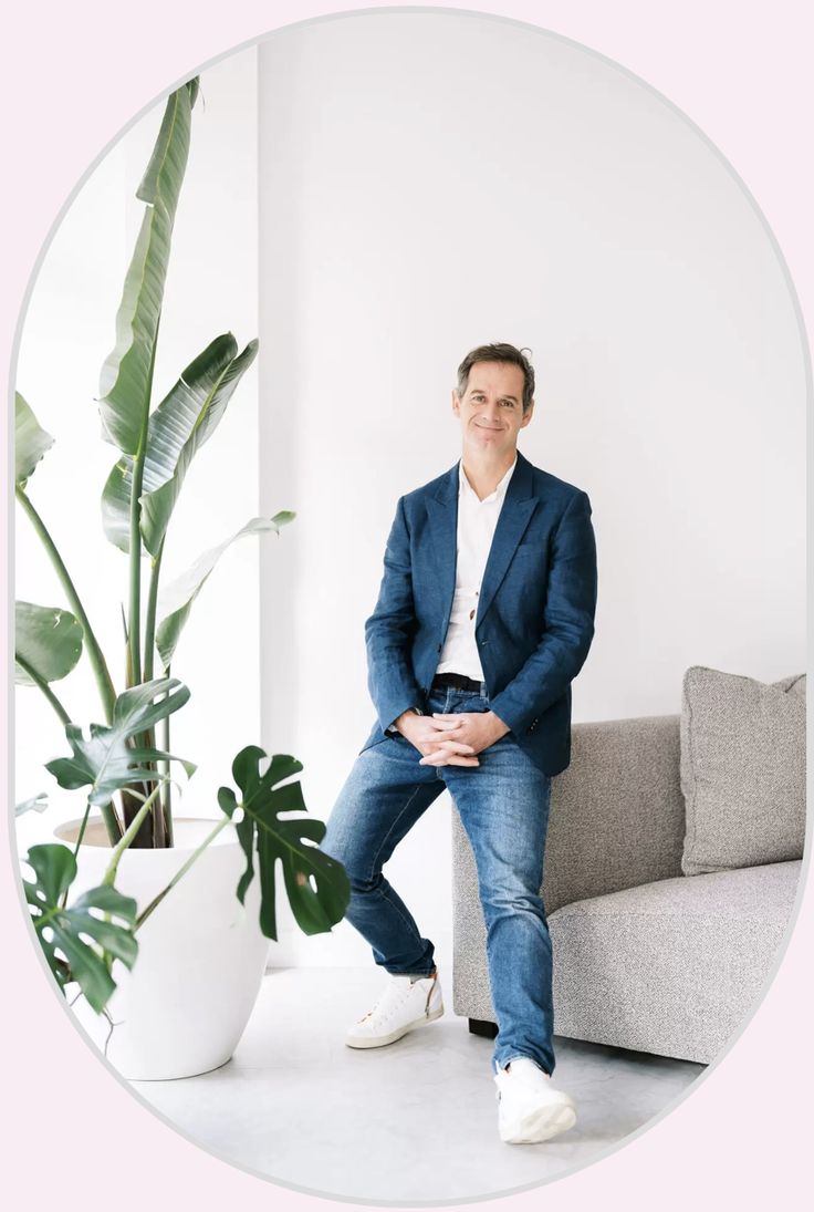 a man sitting on top of a couch next to a potted plant