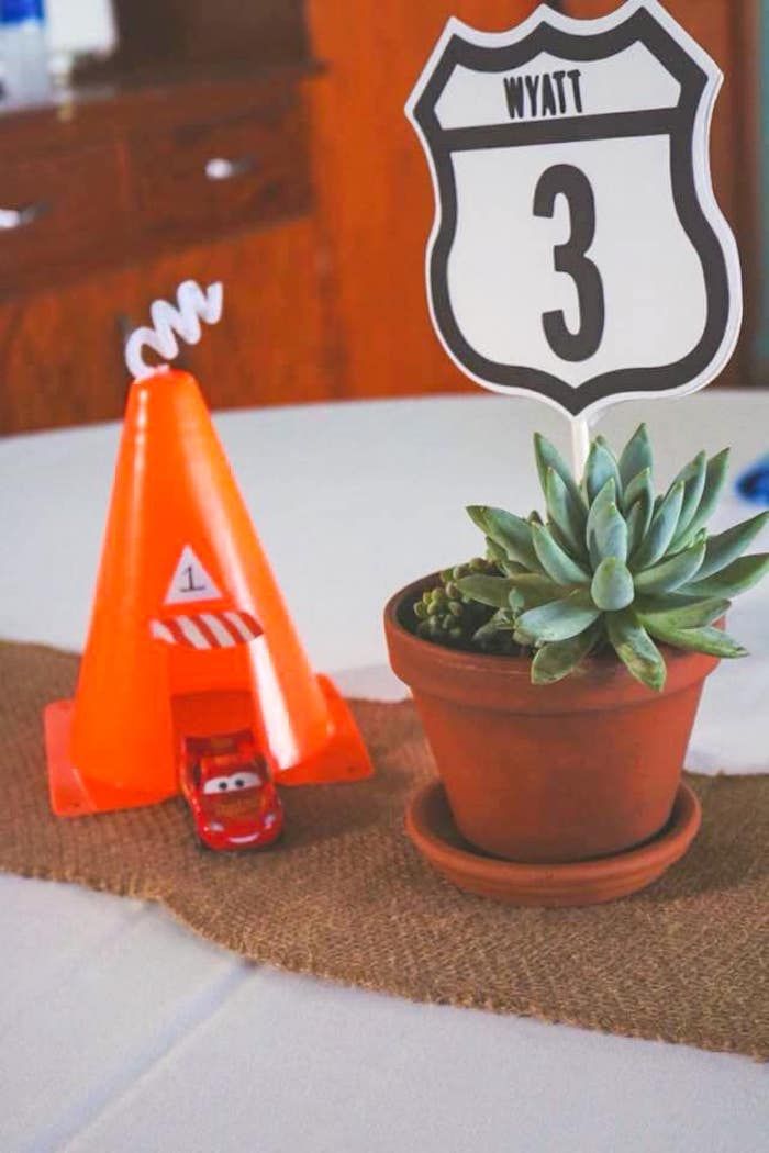 a table topped with a potted plant next to an orange cone and road sign