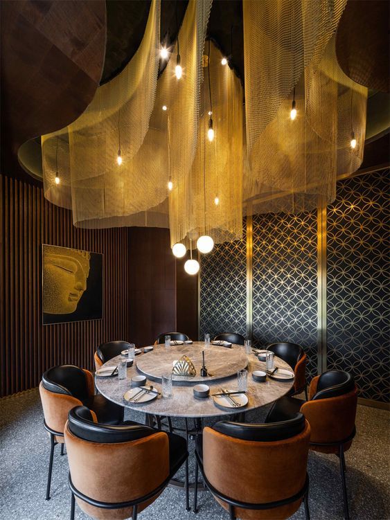 a round table with chairs and lights hanging from the ceiling