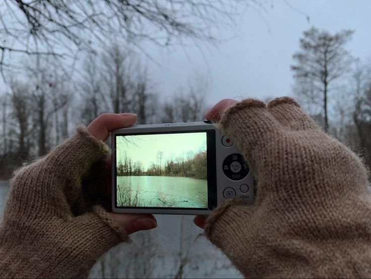 someone taking a photo with their cell phone in the cold snow covered woods and trees