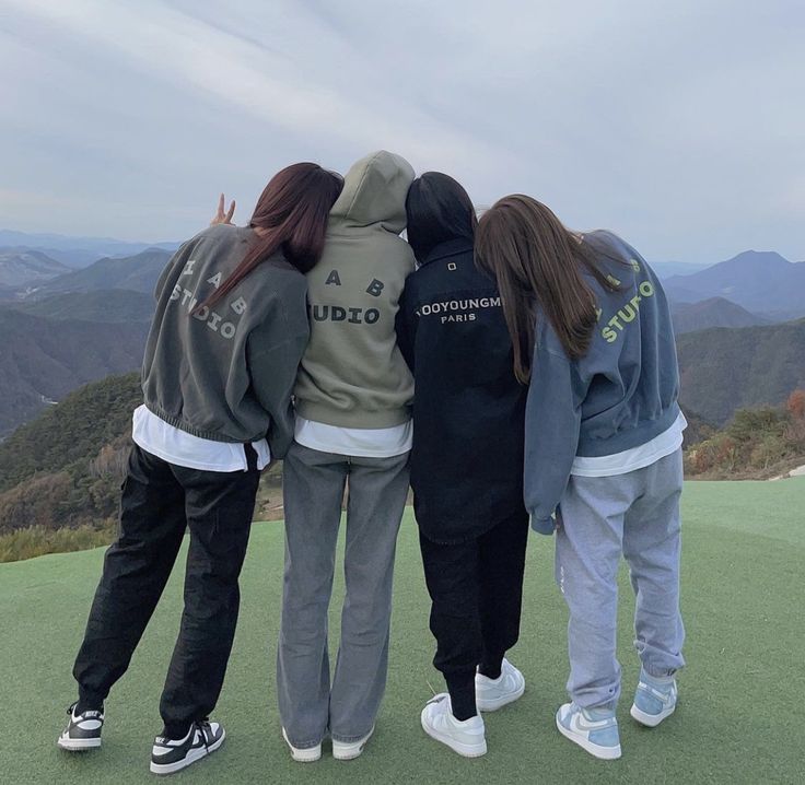 three girls are standing on top of a hill looking at the mountains and hills in the distance