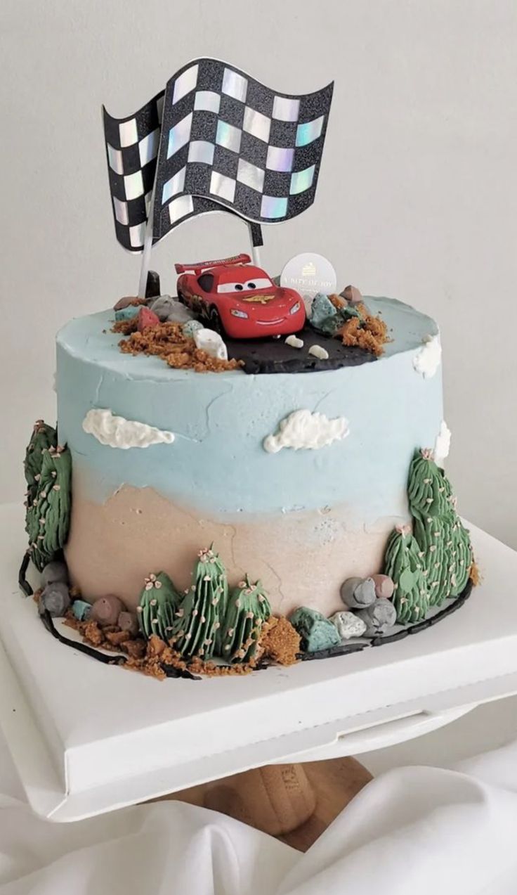 a cake decorated with cars and rocks on a white plate, in the shape of a checkered flag