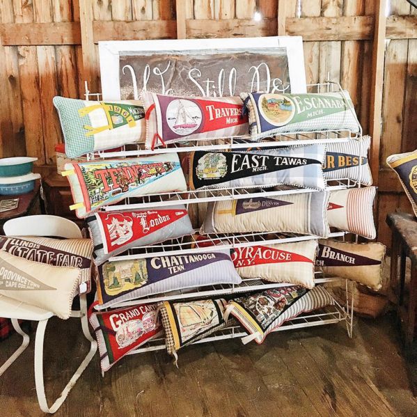 a pile of pillows sitting on top of a wooden floor next to a chair and table