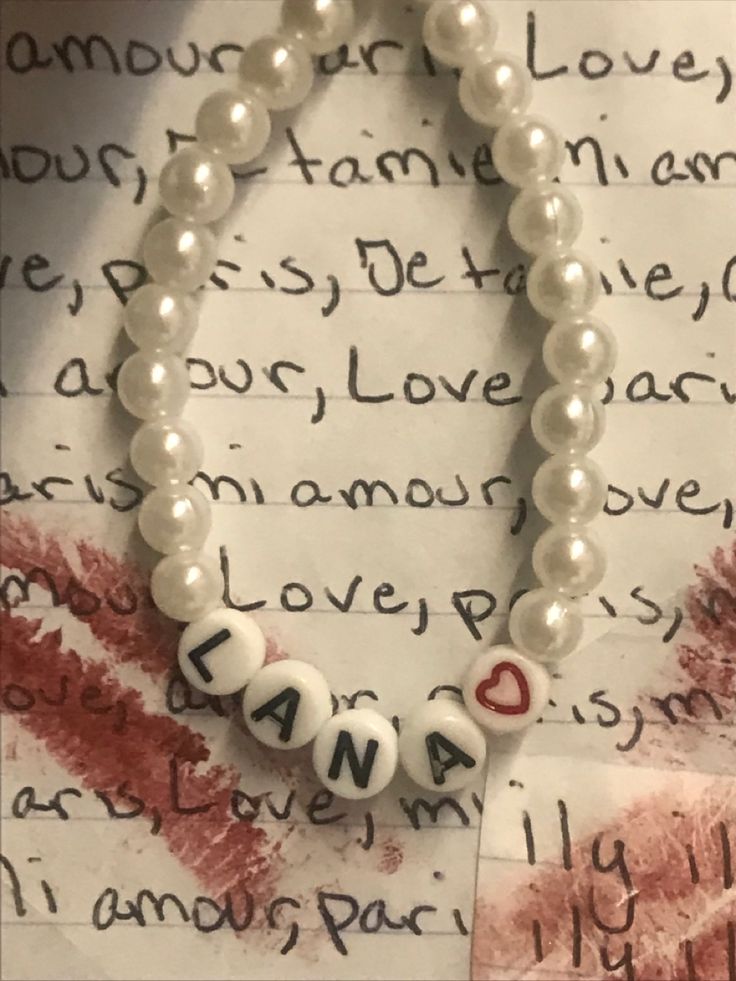 a white beaded bracelet with letters on it and a red heart in the middle