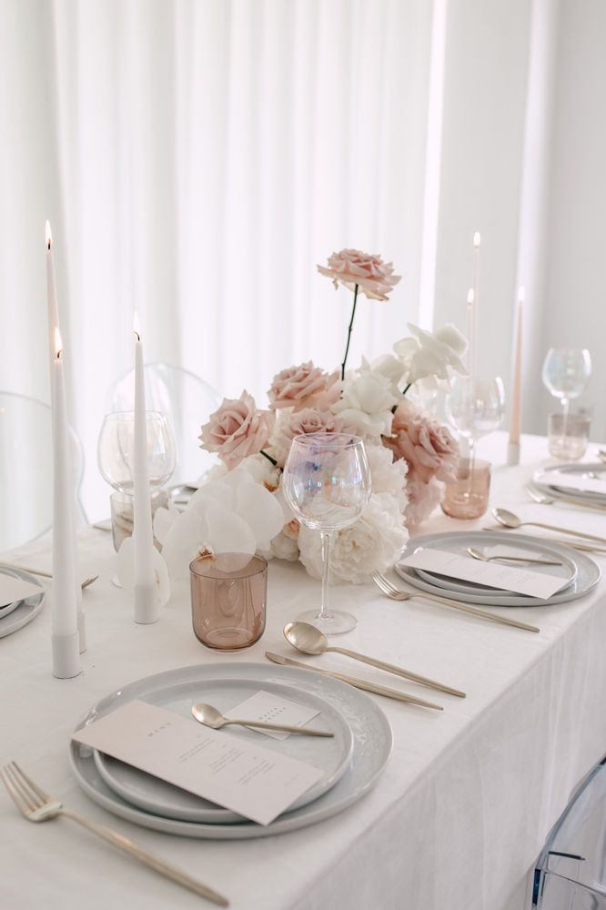 the table is set with silverware and flowers in vases, candles, and napkins