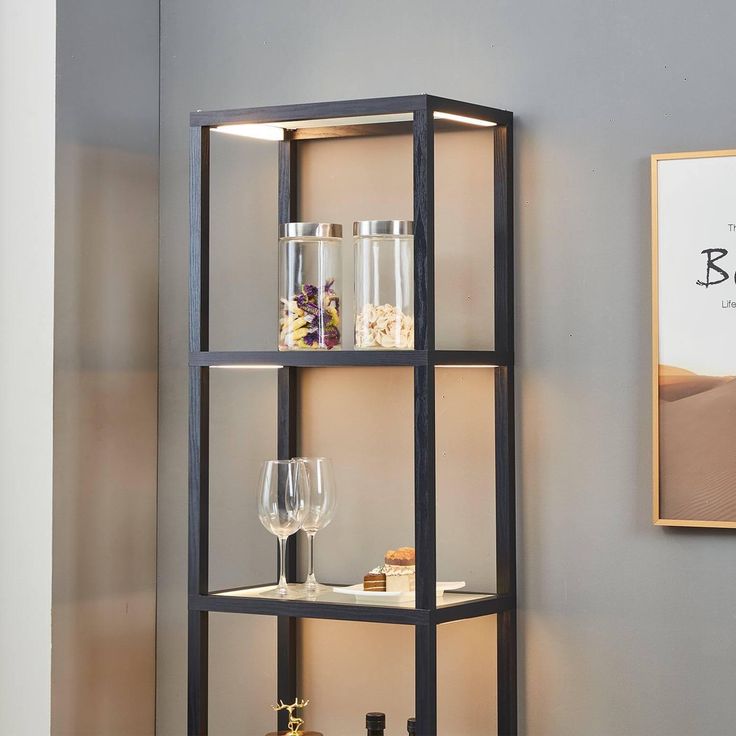 a shelf with wine glasses and bottles on it in front of a wall mounted poster