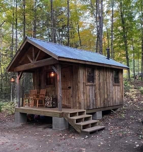 a small cabin in the woods with stairs leading up to it