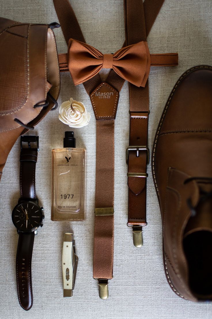 men's accessories laid out on the floor including shoes, cologne bottle and bow tie