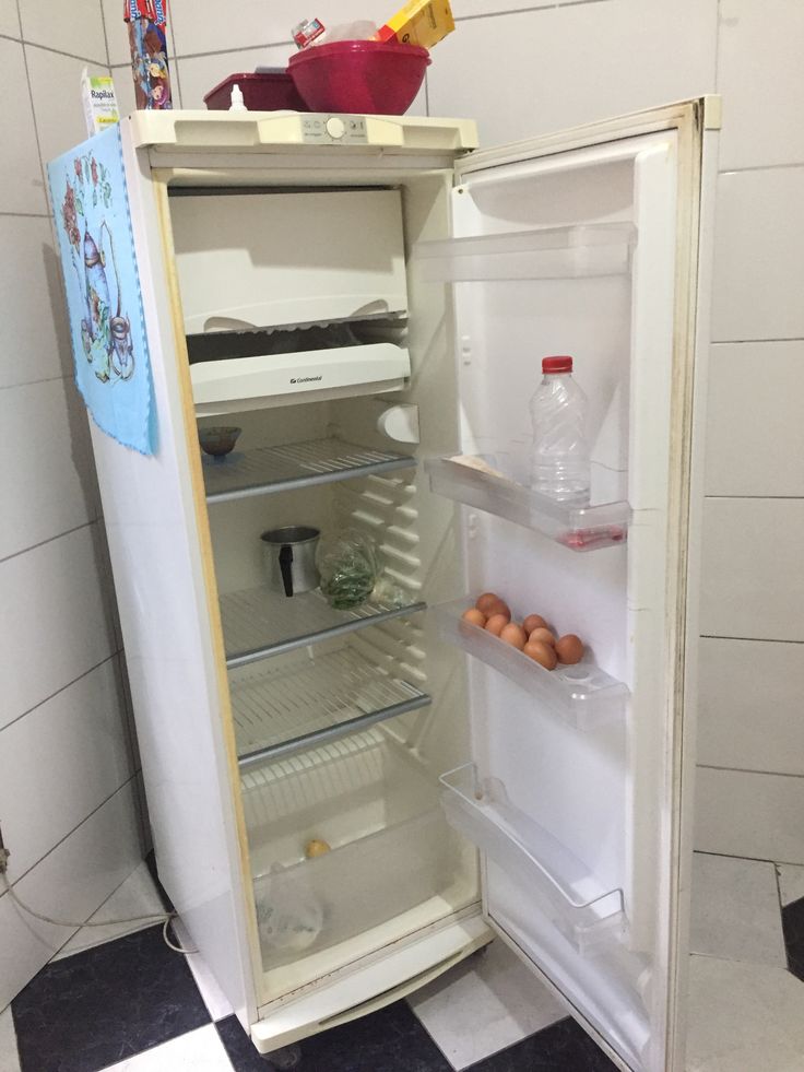 an open refrigerator with eggs in it on a black and white checkerboard floor