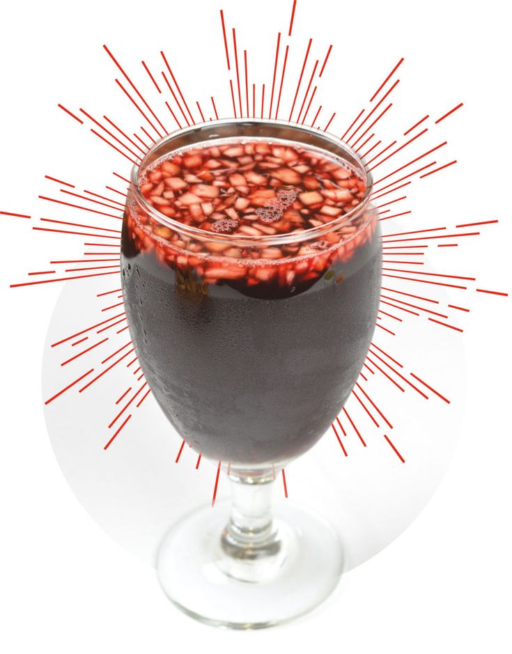 a glass filled with liquid sitting on top of a white table next to a red sprinkle