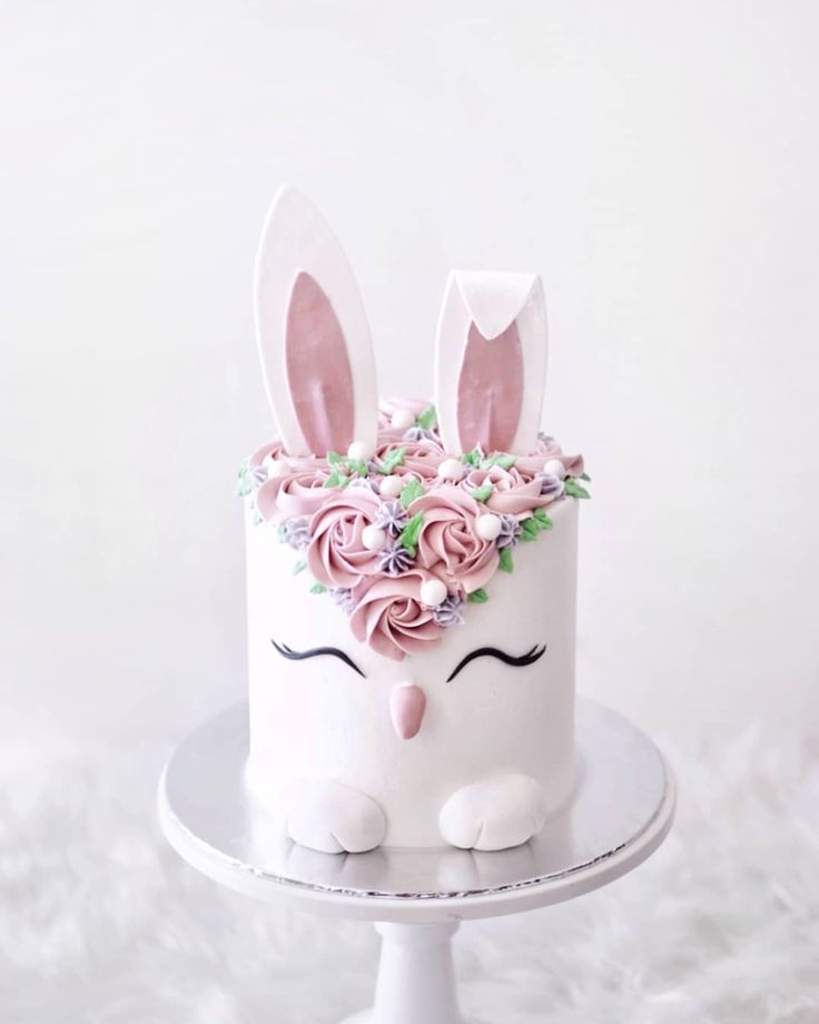 a white cake decorated with pink flowers and bunny ears