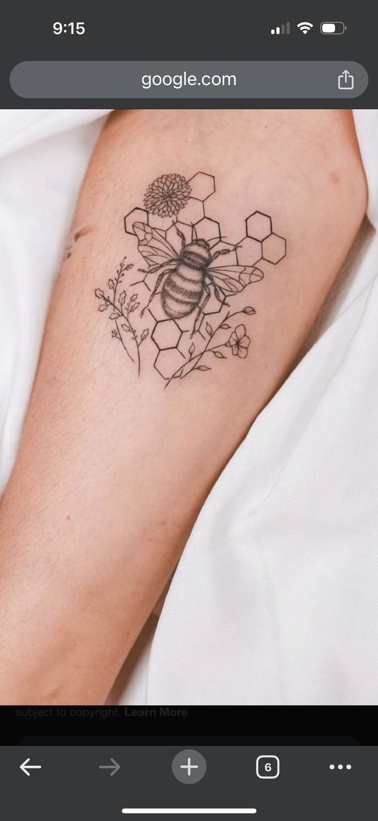 a tattoo on the arm of a woman with flowers and a bee in it's center