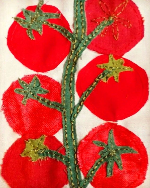 an embroidered piece of cloth with red tomatoes on it and green stems in the center