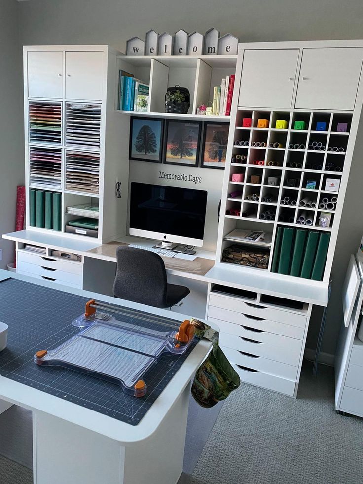 an office with white desks and shelves filled with books, binders and papers