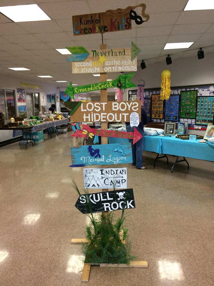 a classroom decorated with lots of signs and plants in the middle of the school hallway