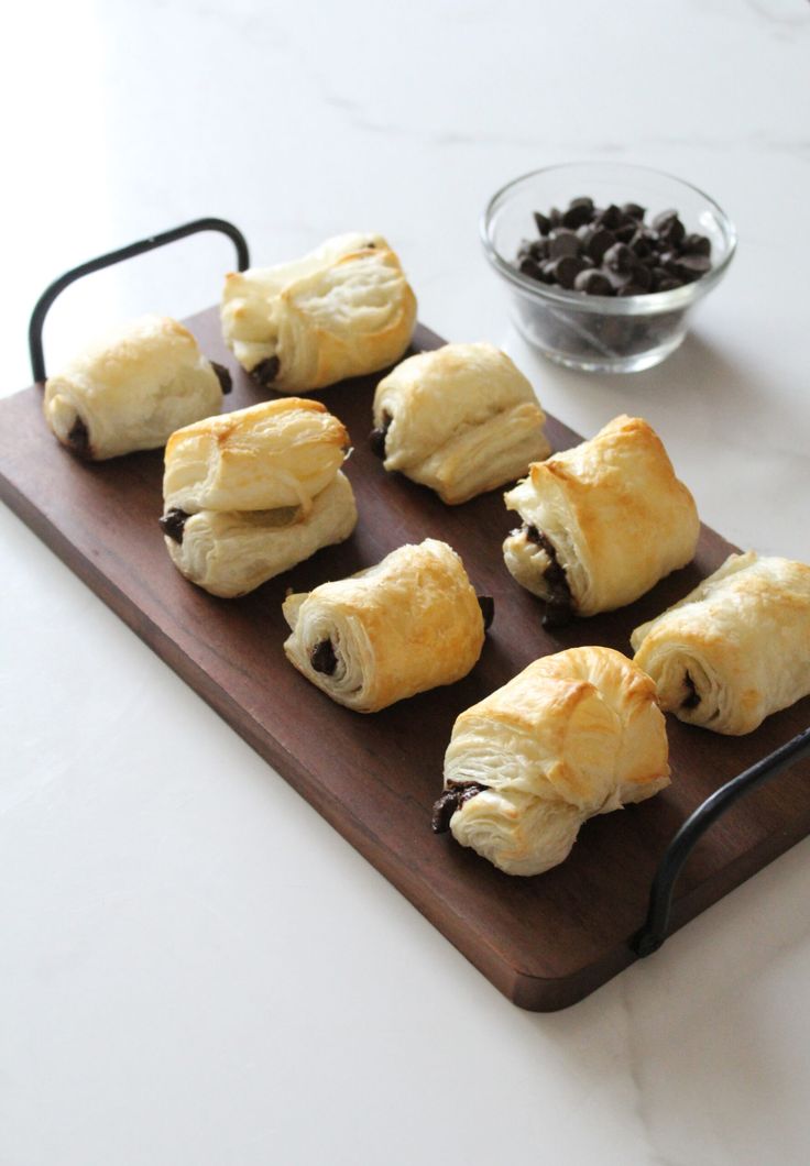 several pastries are arranged on a cutting board with chocolate chips and raisins