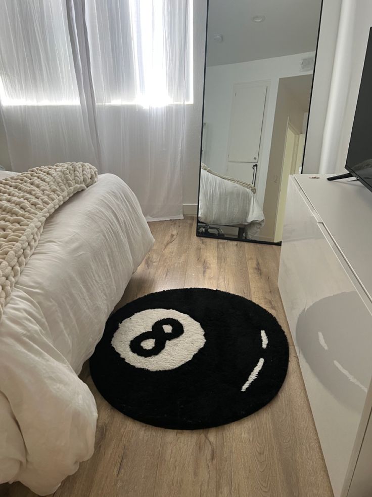 a black and white rug on the floor in front of a bed with a mirror