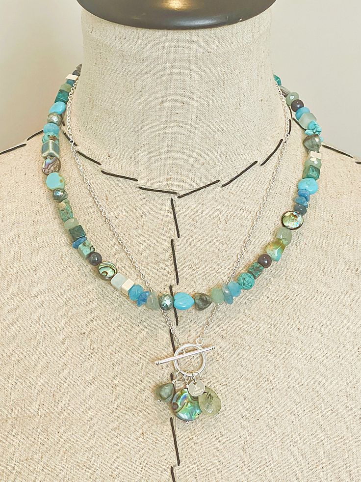 DETAILS Vivid gemstones and hand painted glass in an array of striking turquoise, blue and green hues create an organic pattern in this classic beaded necklace with silver plated hook & eye closure. One of a Kind. Gemstones include: Turquoise (stabilized and natural), Aventurine, Apatite, Aquamarine, Emerald, Abalone, Quartz, Freshwater Pearl. Approximately 18 inches in length. Handmade in Philadelphia, PA USA. SHIPPING + RETURNS Free Priority shipping on US orders over $100. More info 14 day re Toggle Necklace, Organic Pattern, Green Hues, Natural Coral, Painted Glass, Rutilated Quartz, Philadelphia Pa, Multi Stone, Toggle Clasp