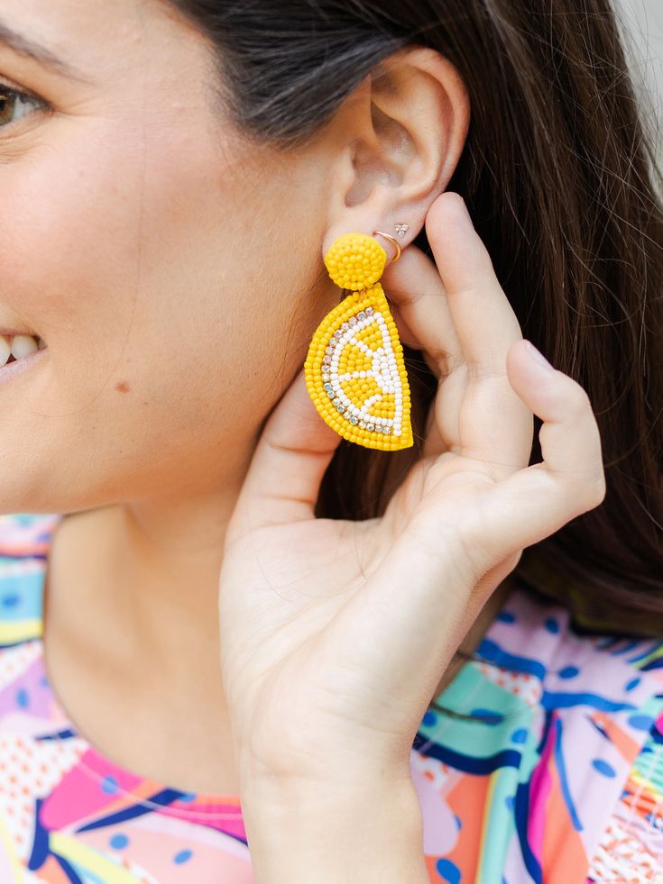 Embrace the zest of summer with our Lemon Earrings. Whether you're strolling through the farmers' market or heading to a sunny brunch, these citrus-inspired earrings will infuse your look with a burst of sunshine and playful charm. Seed bead lemon dangle earrings 2.25" Brass plated Hypoallergenic Surgical steel posts Nickel and lead-free Orange Earrings For Spring Beach Outing, Yellow Earrings For Spring Vacation, Summer Fruit Design Drop Earrings, Summer Fruit Design Earrings, Yellow Beaded Earrings For Summer Beach, Playful Summer Drop Earrings, Summer Orange Drop Earrings, Trendy Yellow Earrings For Summer, Spring Orange Drop Earrings