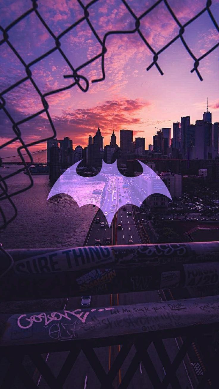 a view of a city skyline through a chain link fence with an umbrella in the foreground