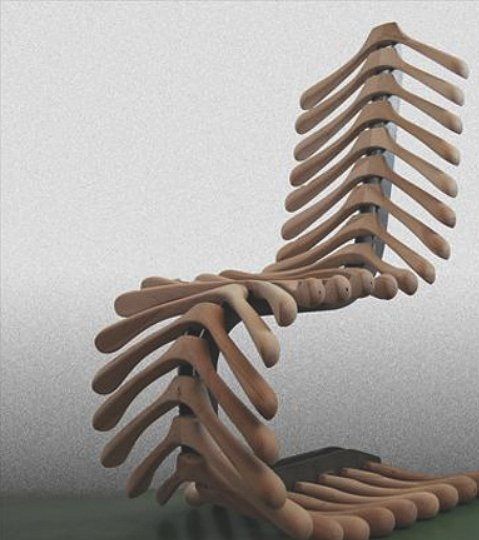 a wooden chair made to look like a human skeleton with long legs and arms, sitting on a green surface