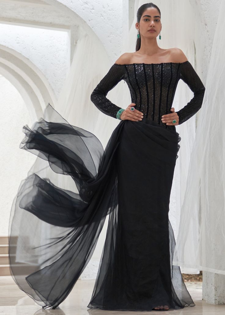 a woman in a black dress with long sleeves and an off the shoulder design on it