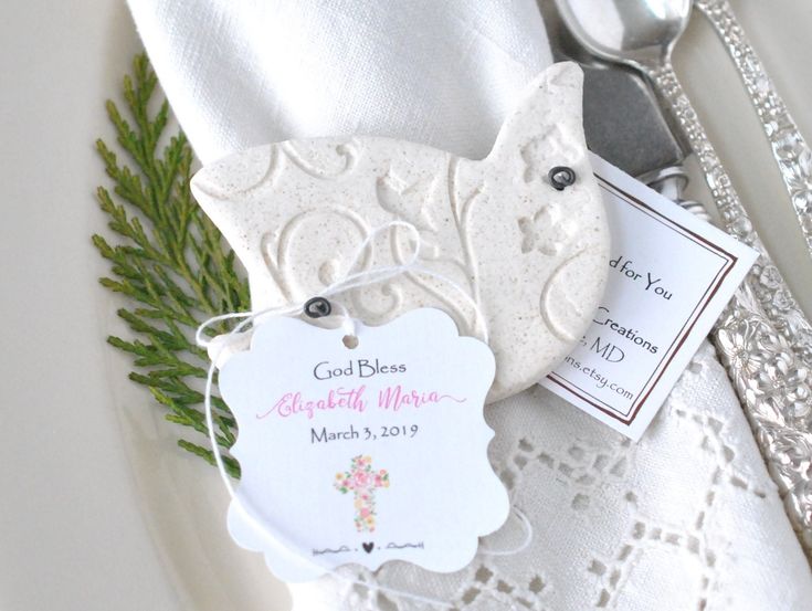 a white plate topped with silverware next to a fork and napkin holder on top of a lace covered table cloth