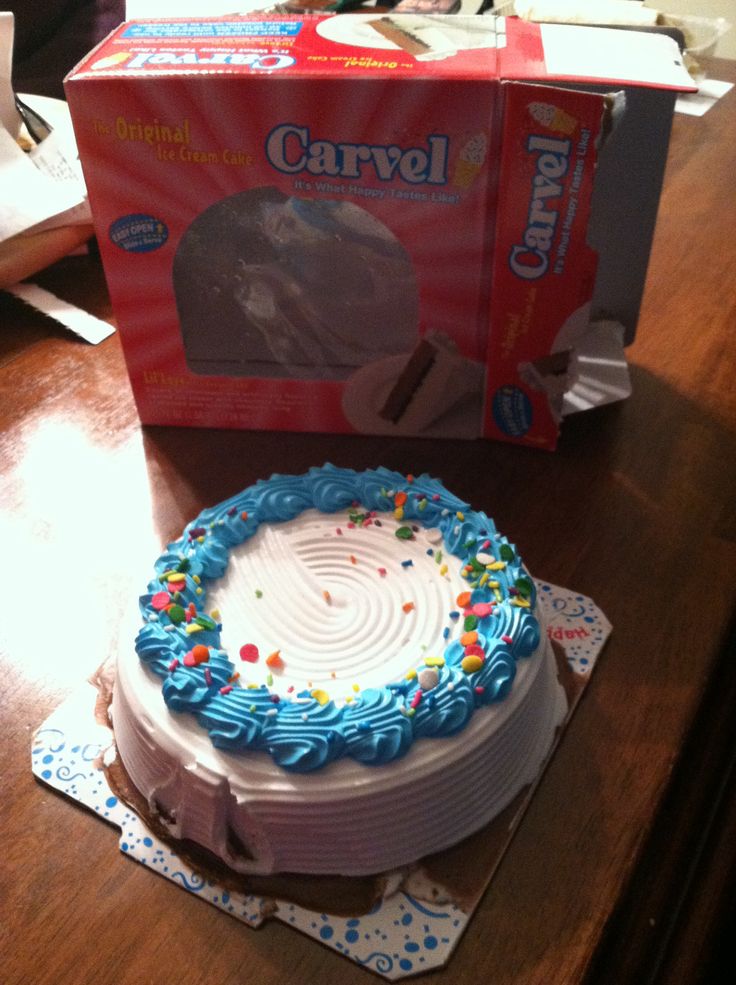 a cake with blue frosting and sprinkles on it next to a box of candy