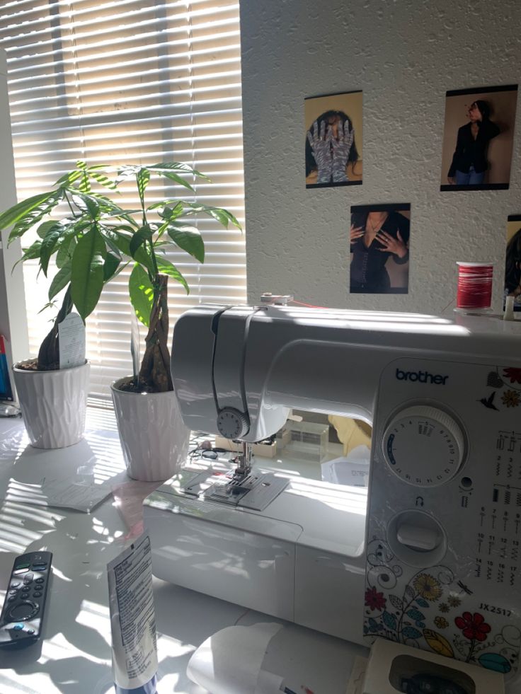 a white sewing machine sitting on top of a table next to a potted plant