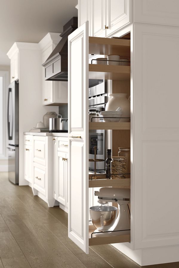 an open cabinet in a kitchen with white cabinets and wood flooring on the side