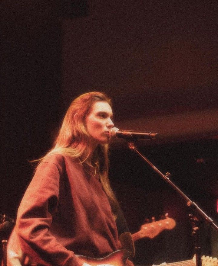 a woman singing into a microphone while holding a guitar