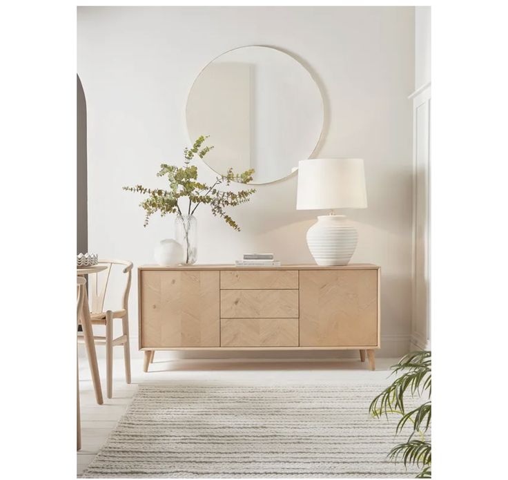 a living room scene with focus on the dresser and round mirror over the top shelf