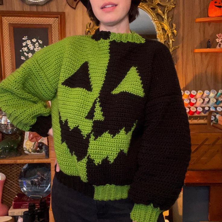 a woman wearing a green and black knitted halloween sweater