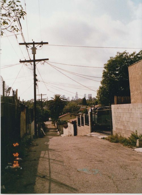 an empty street with power lines above it and buildings in the distance on either side