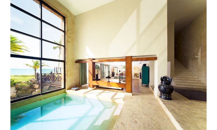 a large indoor swimming pool in the middle of a living room with an ocean view