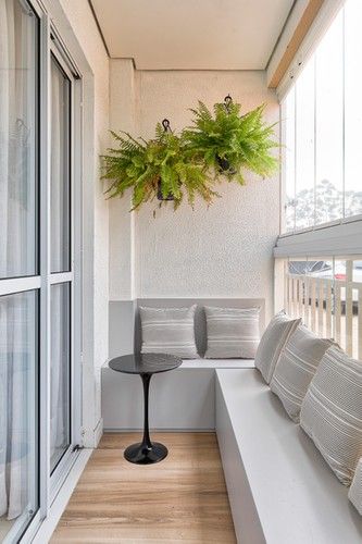 a white couch sitting on top of a wooden floor next to a window covered in plants