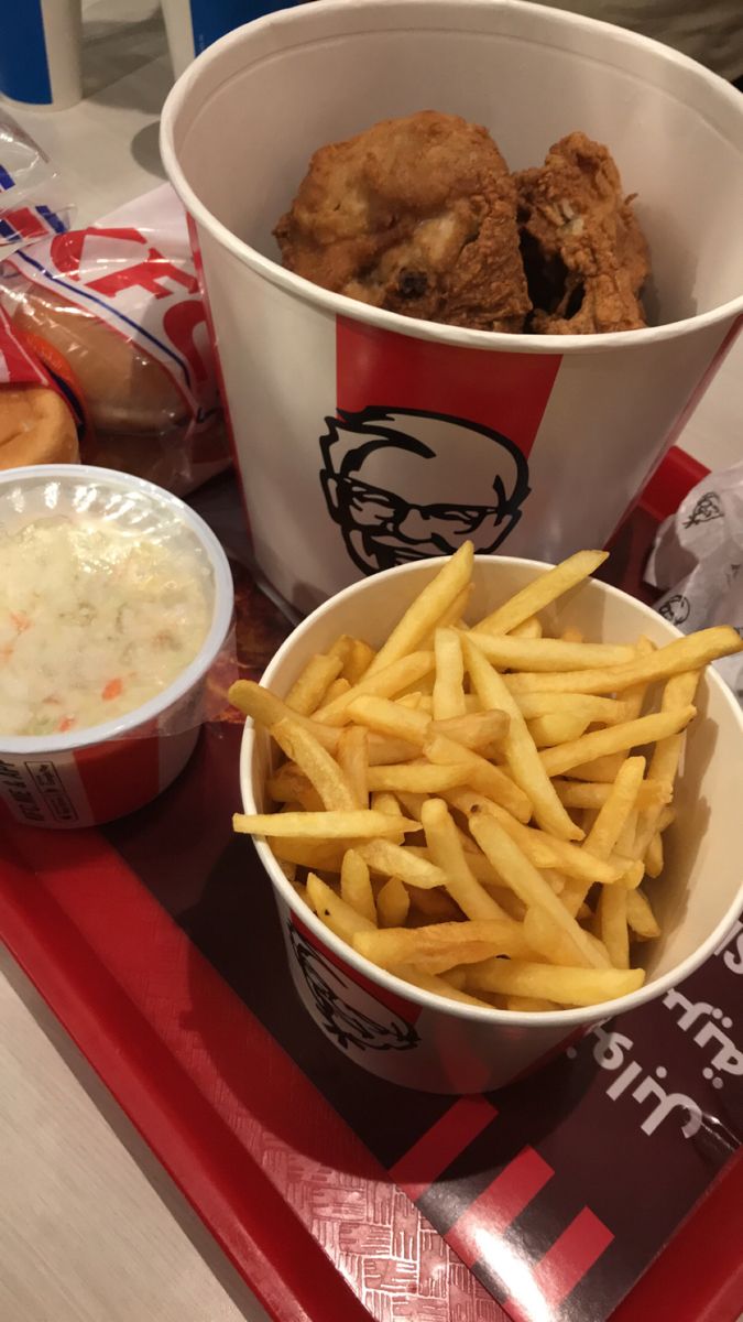 a tray with chicken, fries and coleslaw on it next to a cup of dip