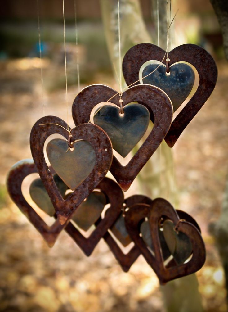 several heart shaped metal ornaments hanging from a tree