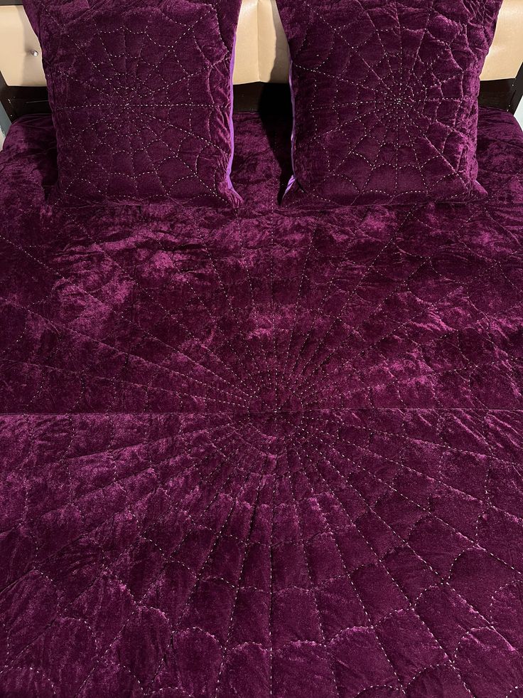 a bed with purple bedspread and two pillows