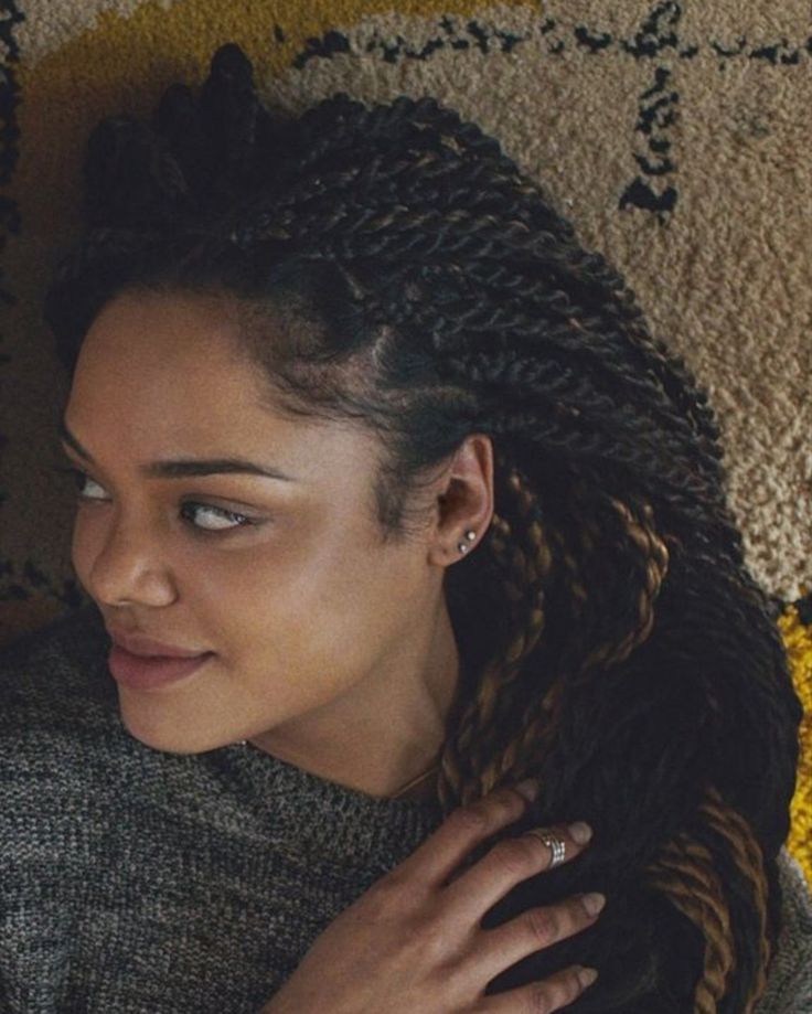 a woman laying on the floor with her hair in braids and wearing a sweater