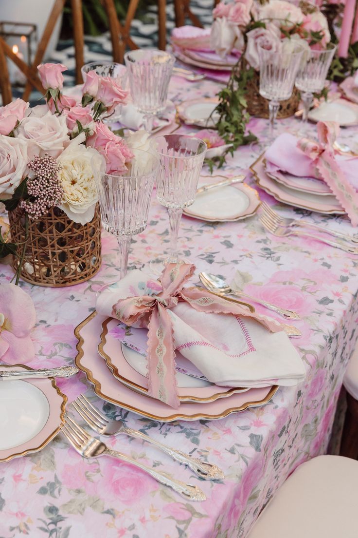 the table is set with pink and white plates, napkins, and silverware