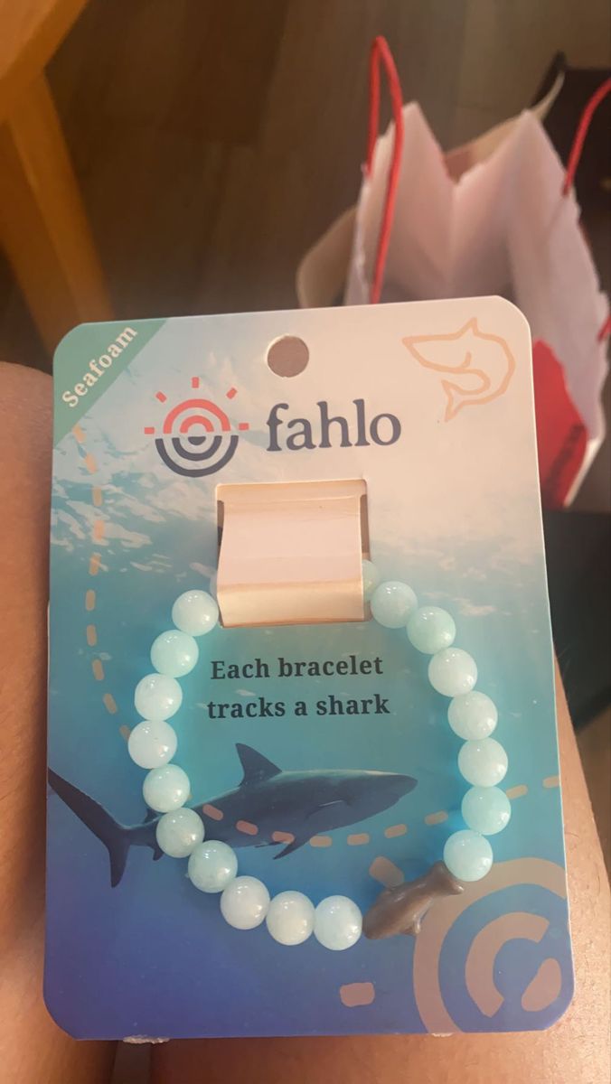 a bracelet with white beads and a shark on it