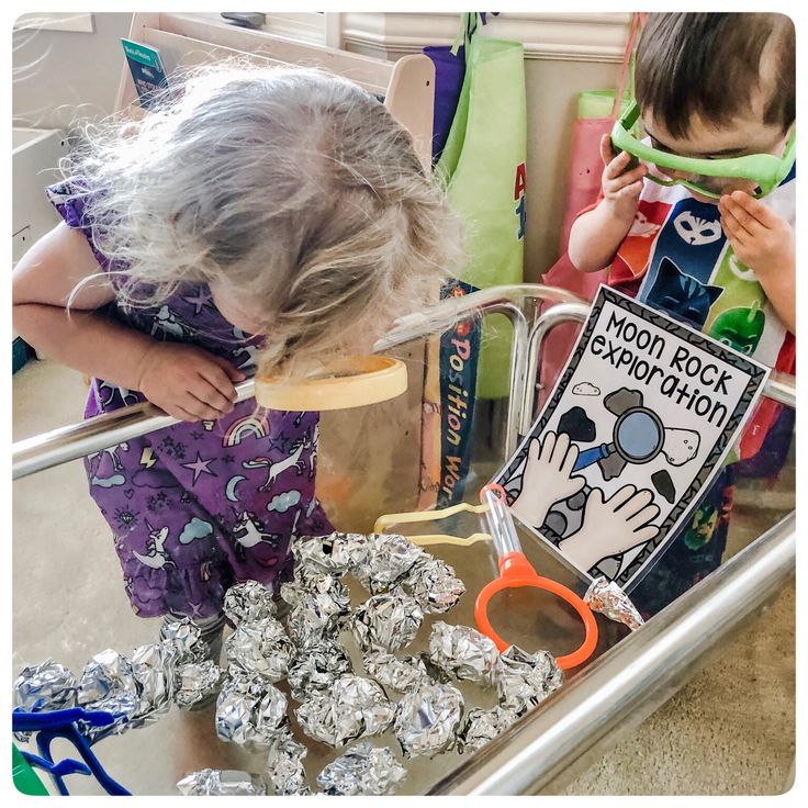 two children are looking at some silver foil