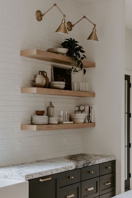 a kitchen with marble counter tops and open shelving above the sink, along with wooden shelves