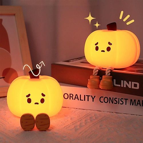 two pumpkin shaped lights sitting on top of a table next to books and a framed photo